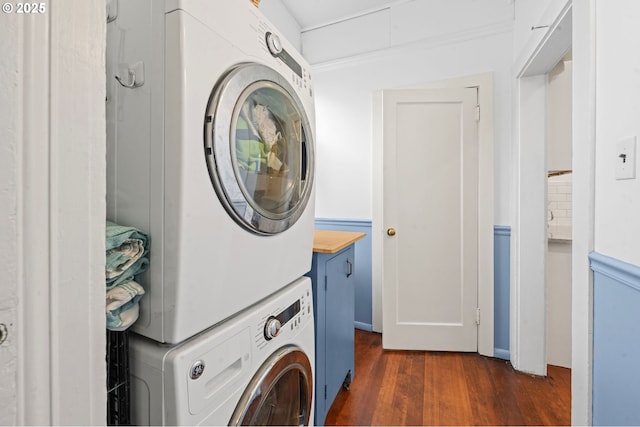 laundry room with estacked washer and dryer, dark wood-type flooring, and cabinet space