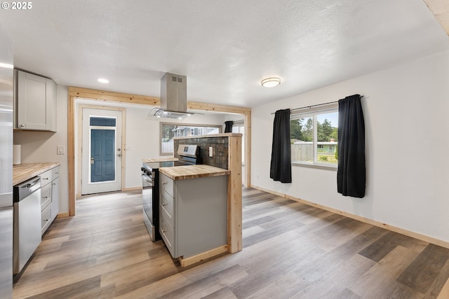 89311 Sutton Lake Dr, Florence, OR 97439 - kitchen featuring stainless steel appliances, wooden counters, island exhaust hood, light wood-type flooring, and plenty of natural light
