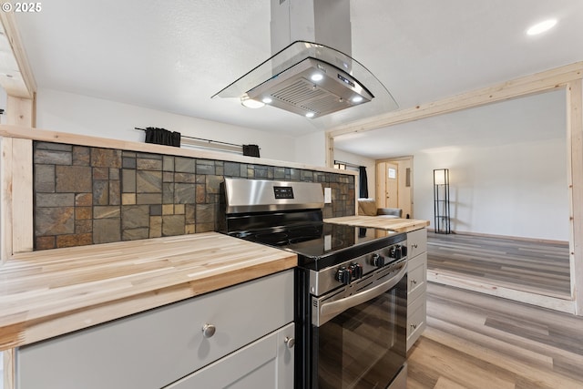 89311 Sutton Lake Dr, Florence, OR 97439 - kitchen featuring stainless steel electric range oven, island range hood, wooden counters, and light wood-style flooring