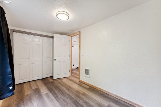 89311 Sutton Lake Dr, Florence, OR 97439 - unfurnished bedroom featuring wood finished floors, a closet, a textured ceiling, and heating unit