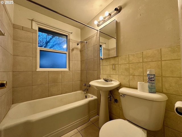 bathroom with tiled shower / bath combo, toilet, tile patterned floors, and tile walls