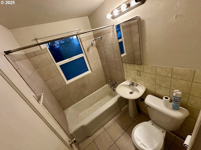 bathroom with tiled shower / bath combo, toilet, tile patterned flooring, and tile walls