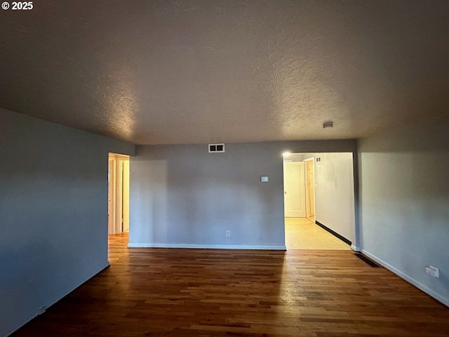 unfurnished room with hardwood / wood-style flooring and a textured ceiling