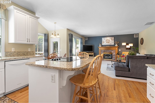 16295 NW Energia St, Portland, OR 97229 - kitchen with white dishwasher, light wood-type flooring, open floor plan, black electric stovetop, and a brick fireplace