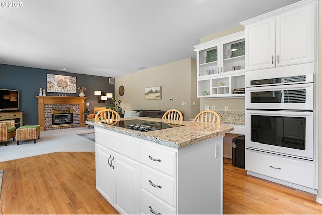 16295 NW Energia St, Portland, OR 97229 - kitchen featuring white double oven, a kitchen island, light wood finished floors, and black electric stovetop