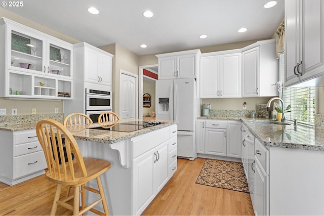 16295 NW Energia St, Portland, OR 97229 - kitchen with white appliances, light wood-type flooring, a center island, a kitchen breakfast bar, and white cabinets
