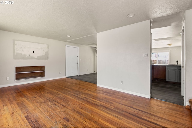 1203 NE 190th Pl, Portland, OR 97230 - unfurnished living room featuring a sink, wood finished floors, a textured ceiling, baseboards, and built in features