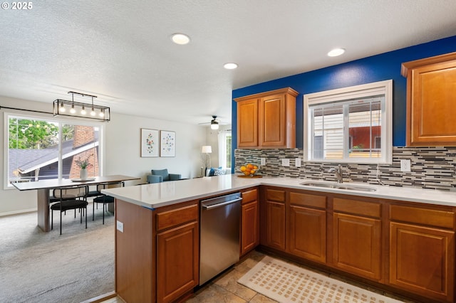 kitchen with dishwasher, a sink, light countertops, a peninsula, and backsplash