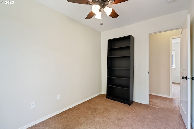 unfurnished bedroom featuring light carpet, baseboards, and ceiling fan