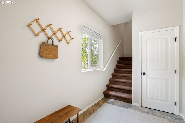 stairs featuring baseboards and stone tile floors