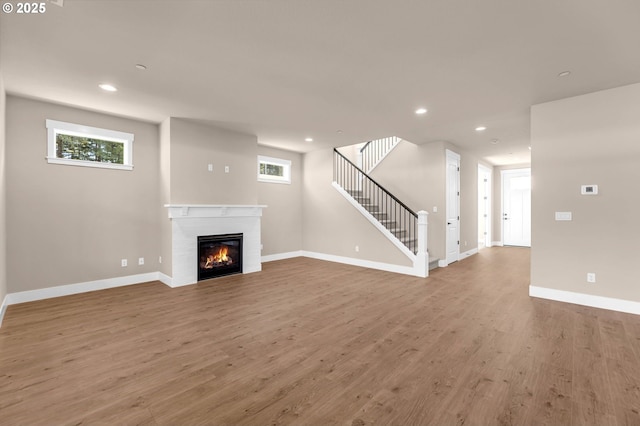 unfurnished living room featuring baseboards, wood finished floors, a fireplace, and recessed lighting