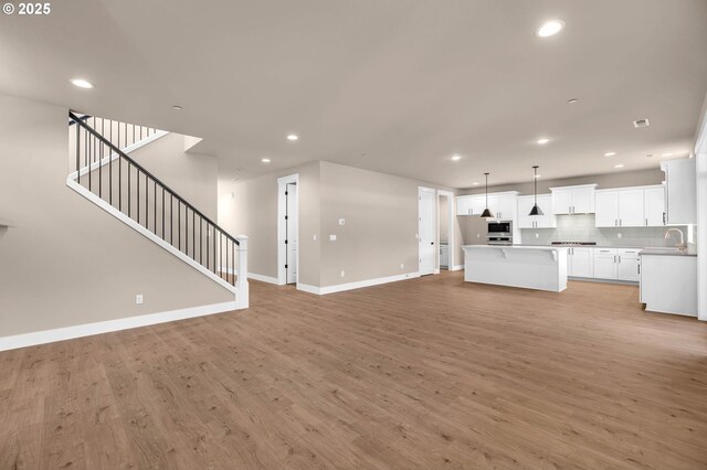 unfurnished living room with light wood finished floors, baseboards, and recessed lighting