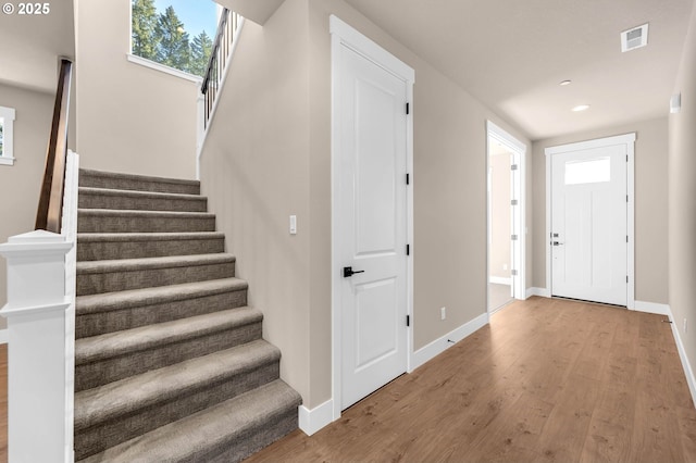 foyer featuring visible vents, baseboards, recessed lighting, wood finished floors, and stairway