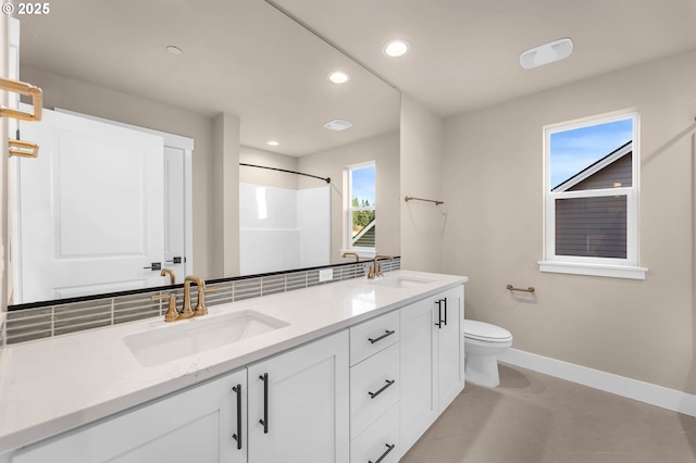 bathroom with baseboards, a sink, recessed lighting, and double vanity
