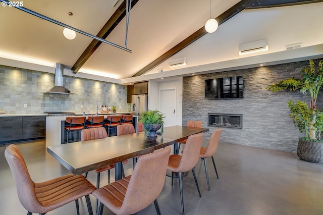 dining area with lofted ceiling with beams, a glass covered fireplace, finished concrete flooring, visible vents, and a wall unit AC