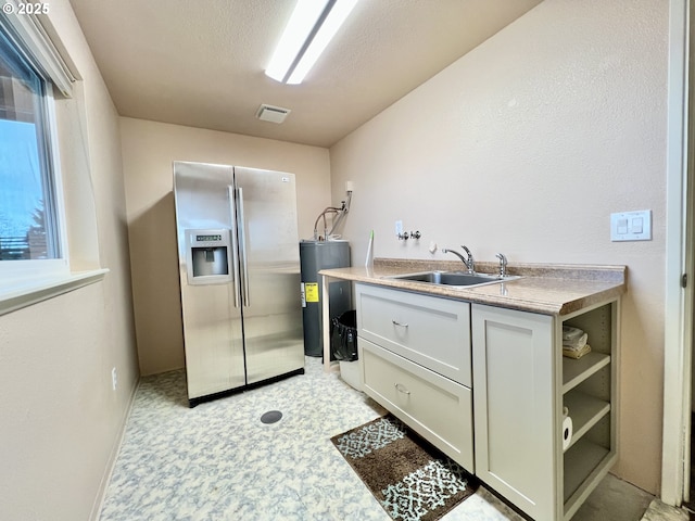 kitchen featuring light floors, open shelves, water heater, a sink, and stainless steel fridge with ice dispenser