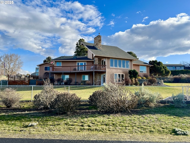 back of property featuring stone siding, fence, and a yard