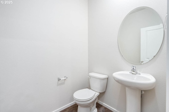 bathroom with baseboards, toilet, and wood finished floors