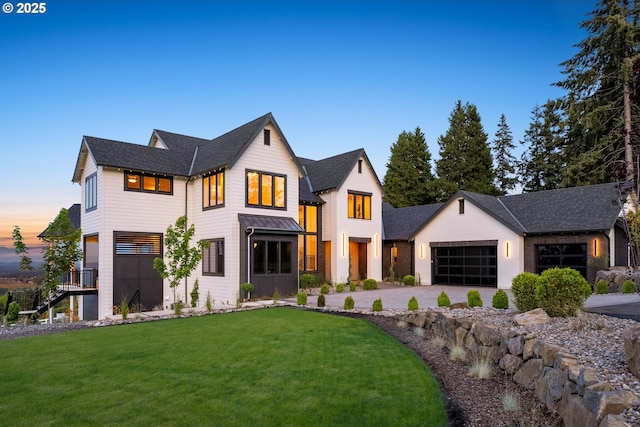 modern farmhouse style home featuring a garage and a lawn