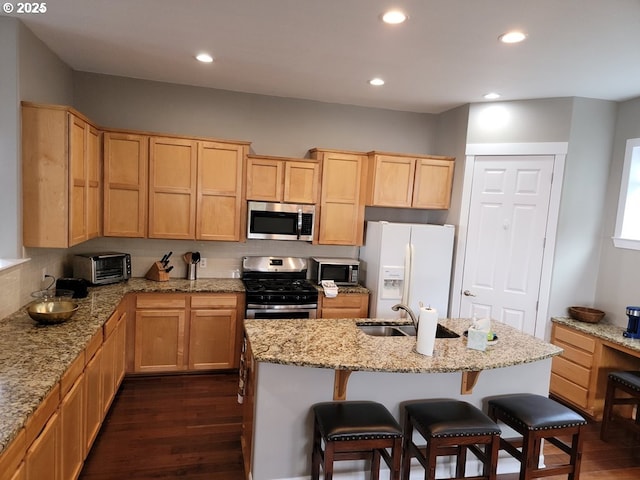 kitchen featuring light stone counters, a kitchen breakfast bar, dark hardwood / wood-style floors, and appliances with stainless steel finishes