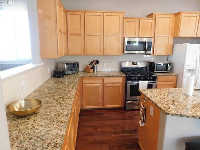 kitchen with stainless steel appliances, tasteful backsplash, light brown cabinets, and dark hardwood / wood-style flooring