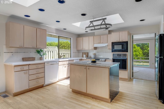 17141 Hofer Ct, Lake Oswego, OR 97034 - kitchen with a skylight, black appliances, light brown cabinetry, under cabinet range hood, and a kitchen island