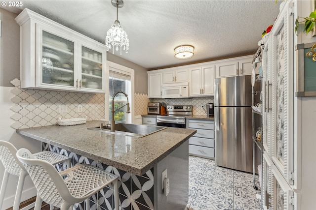 17948 SW Robert Ln, Beaverton, OR 97078 - kitchen featuring appliances with stainless steel finishes, a sink, a peninsula, white cabinets, and decorative backsplash