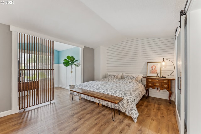 17948 SW Robert Ln, Beaverton, OR 97078 - bedroom featuring a barn door, wood finished floors, lofted ceiling, and wooden walls