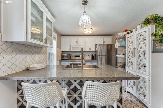 17948 SW Robert Ln, Beaverton, OR 97078 - kitchen featuring stainless steel appliances, white cabinetry, a peninsula, a sink, and a breakfast bar