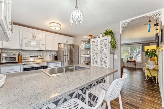 17948 SW Robert Ln, Beaverton, OR 97078 - kitchen featuring stainless steel appliances, white cabinets, dark wood-type flooring, a sink, and decorative backsplash