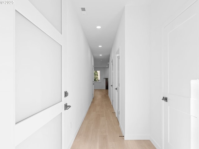 hallway with baseboards, light wood finished floors, visible vents, and recessed lighting