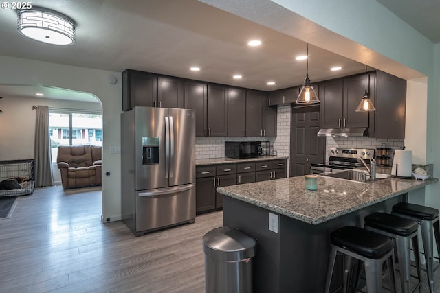 4033 Hanna St, Roseburg, OR 97471 - kitchen with stainless steel appliances, under cabinet range hood, light wood-style flooring, light stone counters, and a kitchen breakfast bar