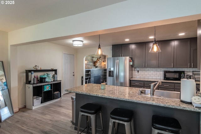 4033 Hanna St, Roseburg, OR 97471 - kitchen with stainless steel refrigerator with ice dispenser, black microwave, a sink, a breakfast bar area, and decorative backsplash