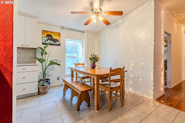 dining space with ceiling fan, light wood-style flooring, and baseboards