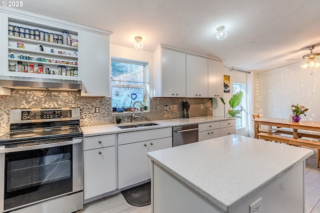 kitchen featuring stainless steel appliances, backsplash, a sink, a kitchen island, and wall chimney exhaust hood