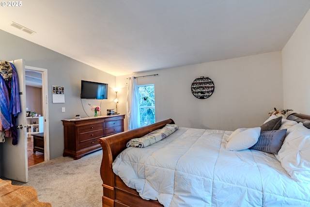 bedroom with visible vents, vaulted ceiling, and light colored carpet