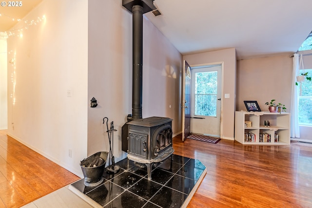 entryway featuring a wood stove, a healthy amount of sunlight, baseboards, and wood finished floors