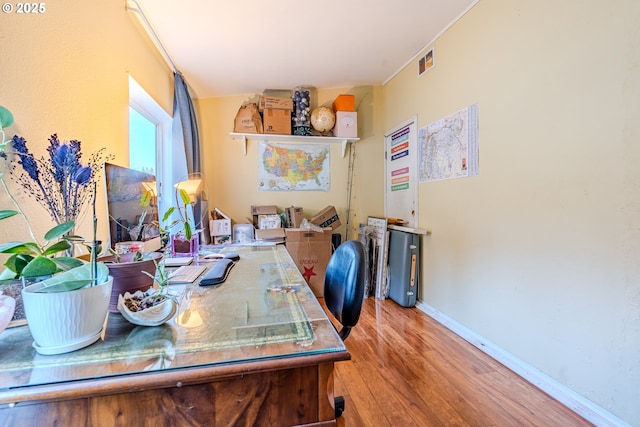 office space with baseboards, visible vents, and wood finished floors