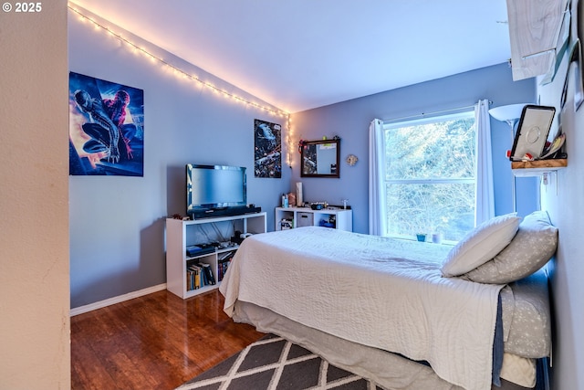 bedroom with lofted ceiling, wood finished floors, and baseboards