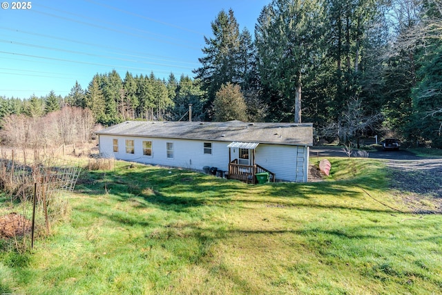 view of front of home featuring a forest view, a front lawn, and driveway