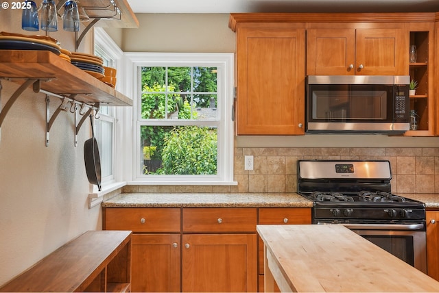 6134 NE 25th Ave, Portland, OR 97211 - kitchen with appliances with stainless steel finishes, wood counters, decorative backsplash, brown cabinets, and open shelves