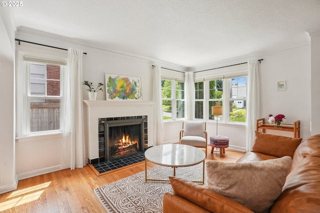 6134 NE 25th Ave, Portland, OR 97211 - living area with a tiled fireplace, crown molding, wood finished floors, and baseboards