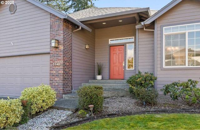 entrance to property with a garage, roof with shingles, and brick siding