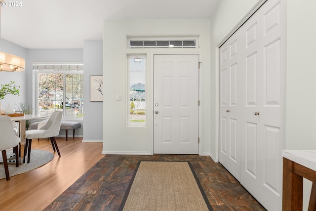 entryway with a chandelier, dark wood-type flooring, and baseboards