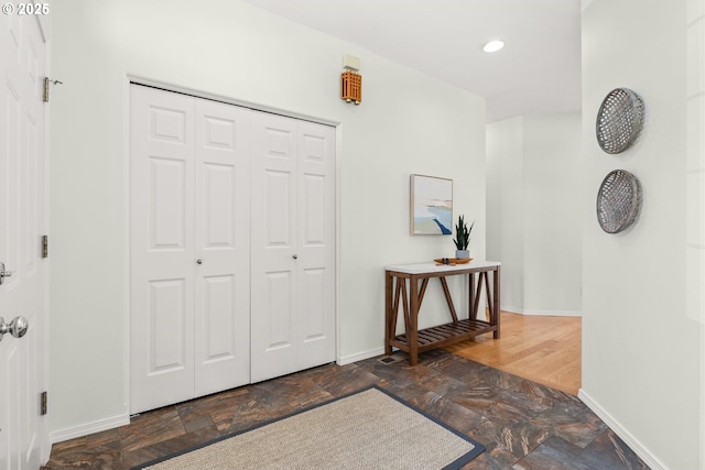 entryway with stone finish flooring, baseboards, and recessed lighting