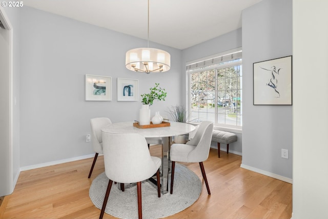 dining space featuring light wood-style flooring, baseboards, and a chandelier