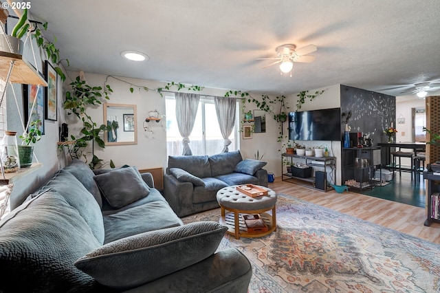 living room with ceiling fan, hardwood / wood-style floors, and a textured ceiling