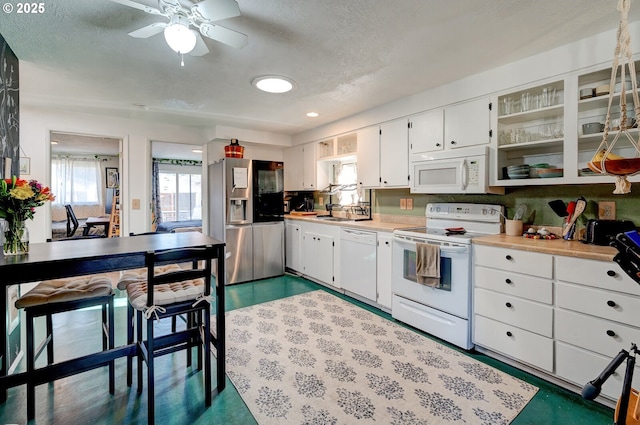 kitchen with sink, white appliances, ceiling fan, a textured ceiling, and white cabinets