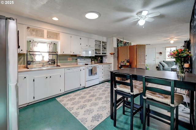 kitchen featuring white appliances, a healthy amount of sunlight, sink, and white cabinets