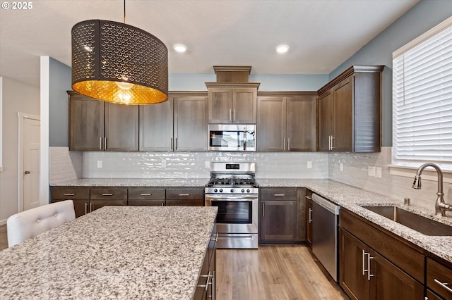 1939 Branch Creek Dr, Longview, WA 98632 - kitchen with appliances with stainless steel finishes, light wood-style floors, light stone counters, pendant lighting, and decorative backsplash